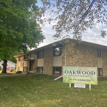 a sign for oakwood apartments is in front of a brick building.