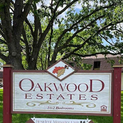 a sign for oakwood estates with a tree in the background.