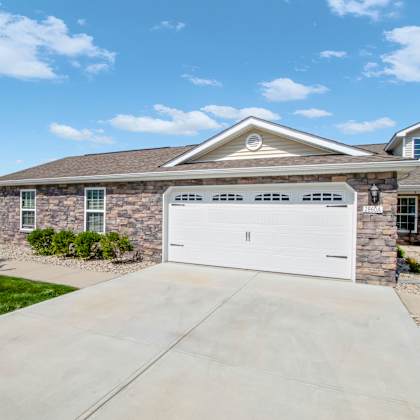 a house with a white garage door and a stone wall.
