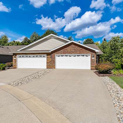 a house with a white garage door is surrounded by a gravel driveway and a grassy lawn.