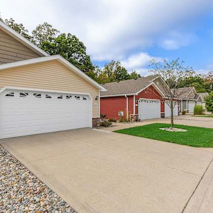 a house with a red garage door is surrounded by a gravel driveway and a grassy area.