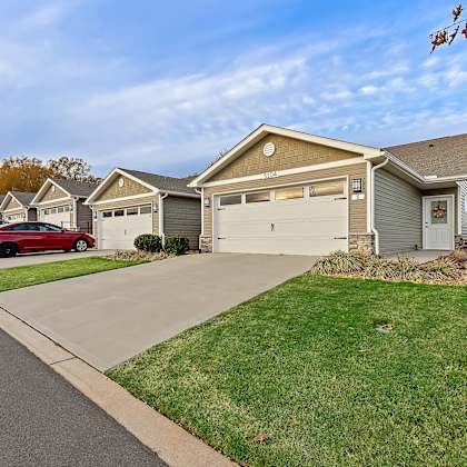 a red car is parked in front of a house with a garage.