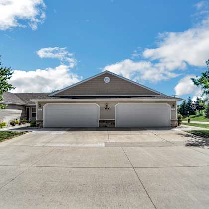 a two-car garage with a brown roof is situated in front of a house.