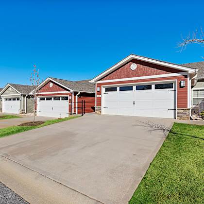 a red house with a white garage door is in front of other houses.