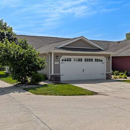 a house with a red garage door is surrounded by a concrete driveway and a green lawn.