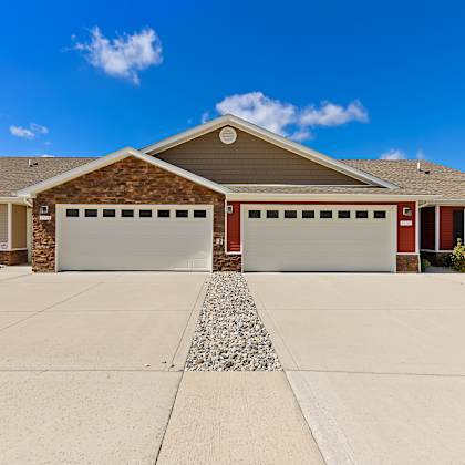 a two-car garage is attached to a brick house.
