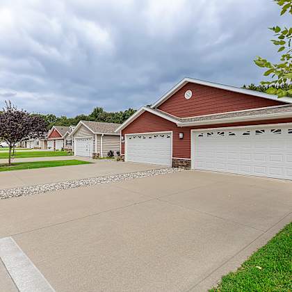 a red house with a white garage door is in front of a tree.