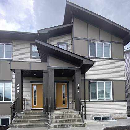 a modern house with a grey exterior and a brown front door.