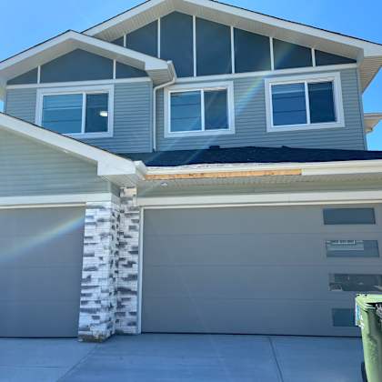 a modern house with a grey roof and a white garage door.