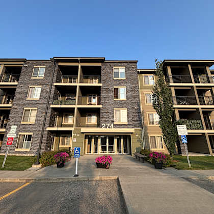 apartment building with a blue sign in front.