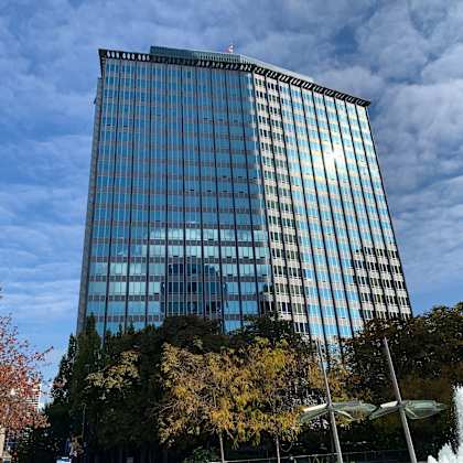 a tall glass building with a fountain in front of it