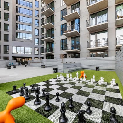 a giant chess board with pieces on a lawn in front of a building.