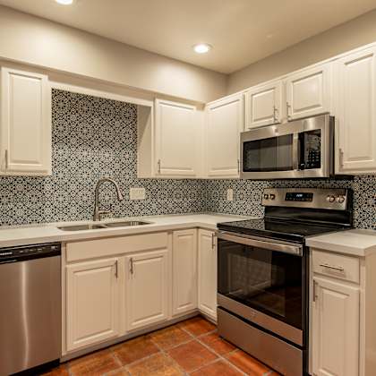 a kitchen with white cabinets and stainless steel appliances