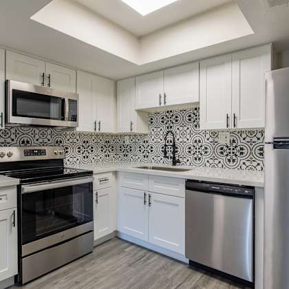 a kitchen with white cabinets and stainless steel appliances