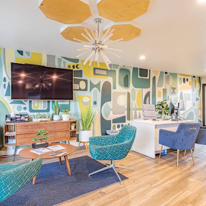 a living room with blue chairs and a table and a television