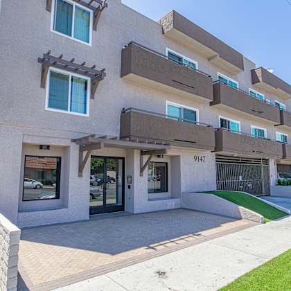 a view of the front of a building with a sidewalk and grass