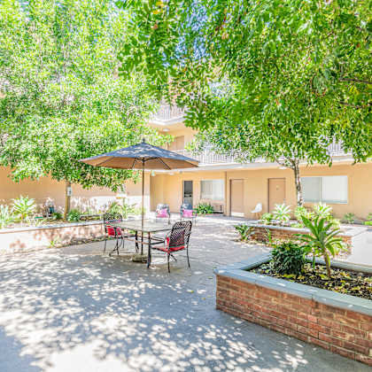 a patio with a table and chairs under a tree.