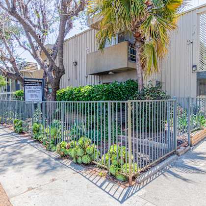 a yard with a fence and plants in front of a building