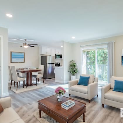 a well-lit living room with a dining area in the background.