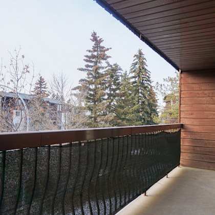 a balcony with a black railing and a view of trees and buildings.