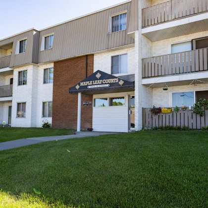 maple leaf courts is a residential building with a green lawn in front.