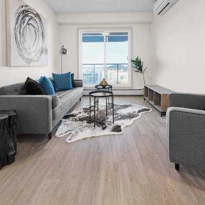 a living room with a grey couch, a black stool, and a rug.
