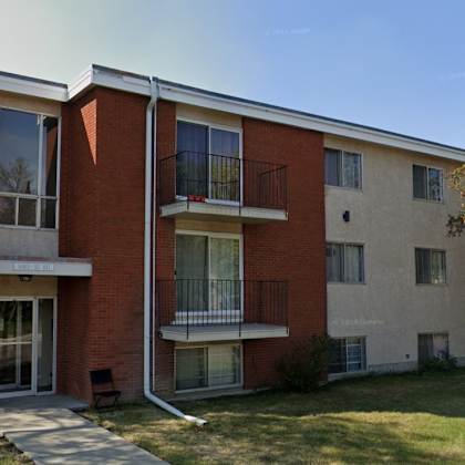 a red brick building with a balcony and a glass door.
