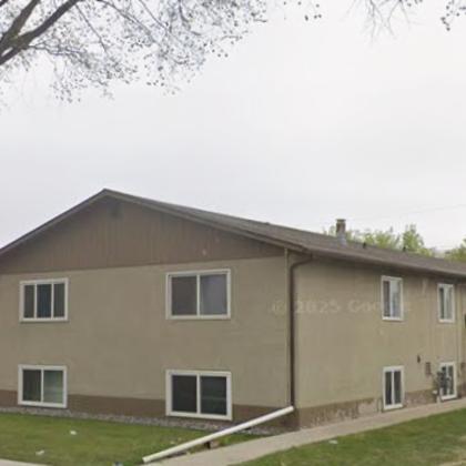 a beige two-story apartment building with a brown roof.