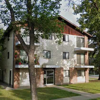 a large tree is in front of a two-story building.