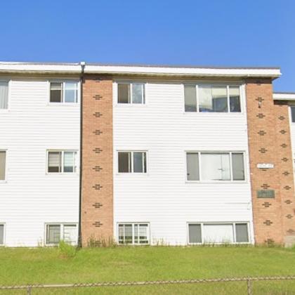 a white and brown building with a green lawn in front.