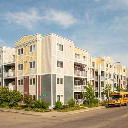 a row of apartment buildings with a school bus in front.
