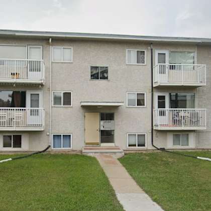 a large apartment building with a green lawn in front.