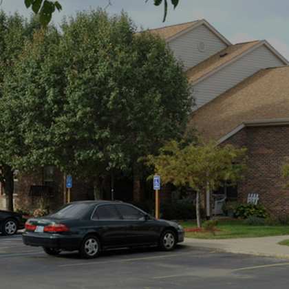 a black car is parked in a parking lot in front of a building.