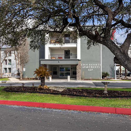 a tree in front of a building with the words "den heights apartments" on it.