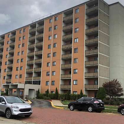 a large apartment building with cars parked in front.