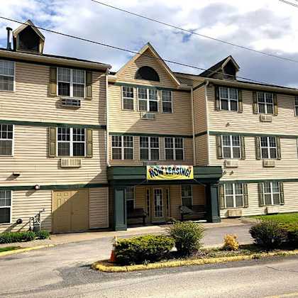a multi-story apartment building with a sign that says "now leasing".