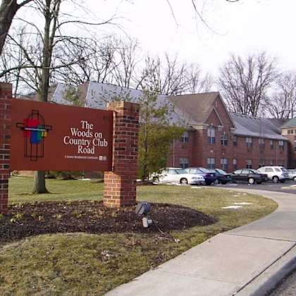 a sign for the woods on country club road stands in front of a building.