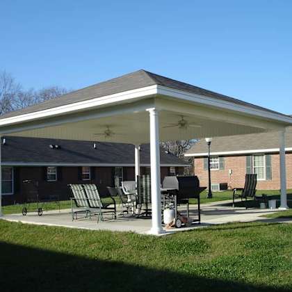 a covered patio area with chairs and a grill.