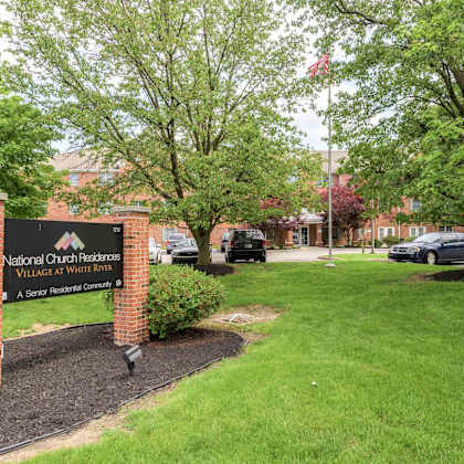 a sign for national church residence village at whit river stands in front of a green lawn.