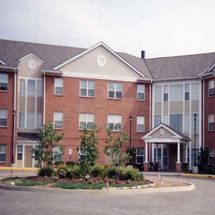 a large red brick building with a landscaped front yard.