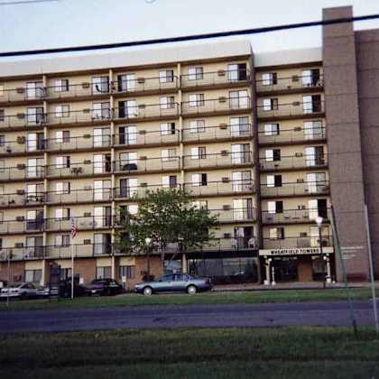 a tall apartment building with a parking lot in front.