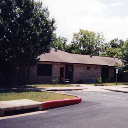 a building with a brown roof and a tree in front of it.