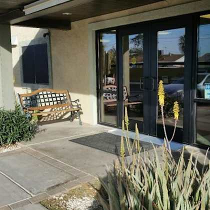 a bench is placed outside a building with glass doors.