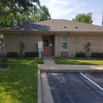 a small brick building with a brown door and a sign that says "community hall" on the front.
