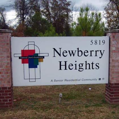 a sign for newberry heights residential community stands in front of a brick wall.