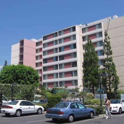 a blue car is parked in a parking lot in front of a multi-story building.