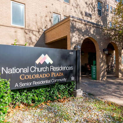 a sign for national church residences colorado plaza stands in front of a building.
