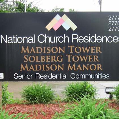 a sign for national church residences with three towers listed.