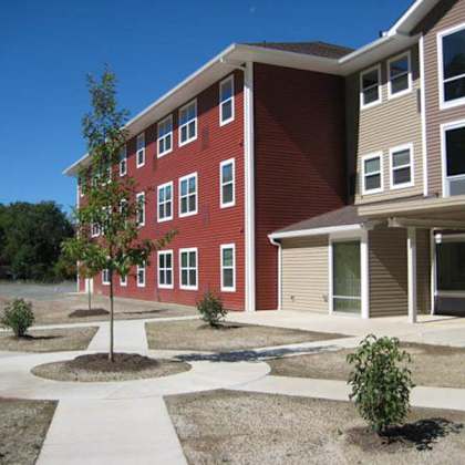 a red and beige building with a tree in front.