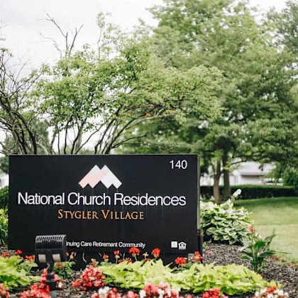 a sign for national church residences styler village is displayed in front of a garden.